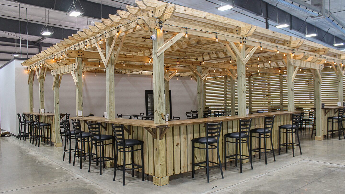 The timber pergola and its bar seating inside Dual Cities NWA, string lights strung between the posts.