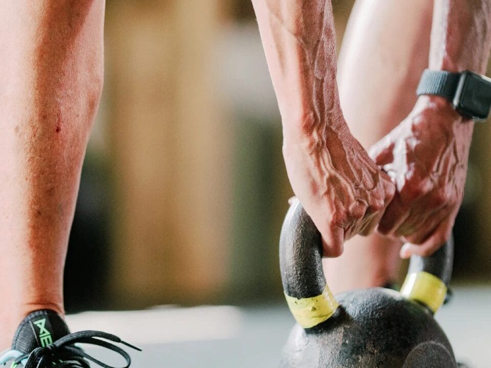 Hands gripping kettlebell handles mid-workout at the CrossFit gym.