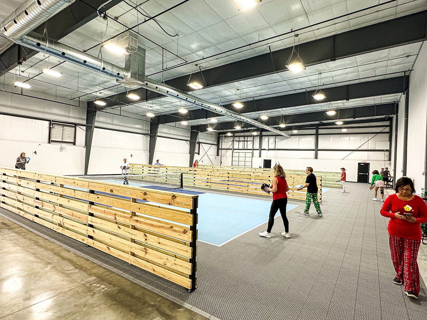 Players mid-rally on the indoor pickleball courts at Dual Cities NWA.